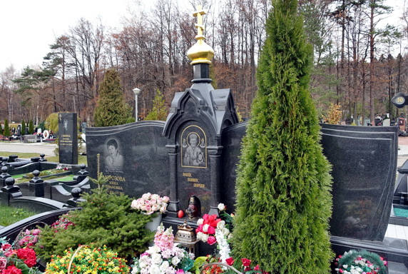Высокая туя перед широкой мемориальной композицией в православном стиле